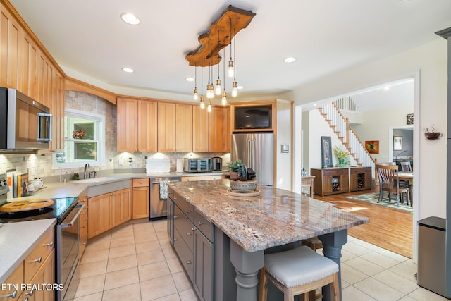 kitchen with a breakfast bar area, light tile patterned flooring, appliances with stainless steel finishes, tasteful backsplash, and a center island