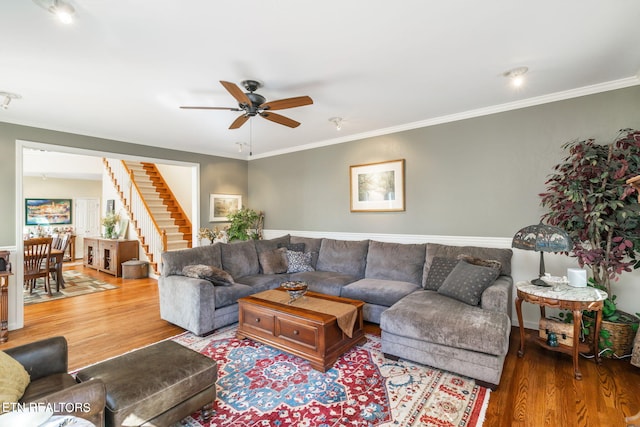 living room with ornamental molding, stairs, ceiling fan, and wood finished floors