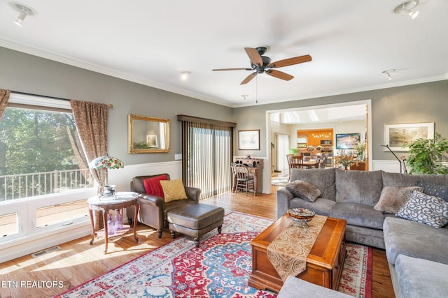 living area featuring visible vents, ornamental molding, ceiling fan, and wood finished floors