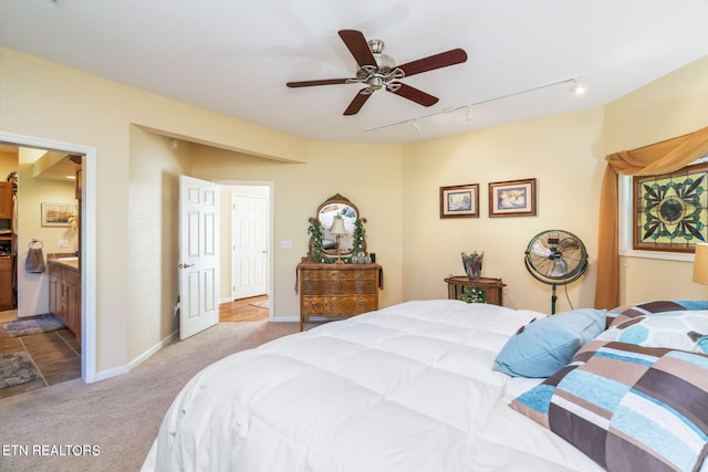 bedroom with baseboards, ensuite bath, ceiling fan, track lighting, and light colored carpet