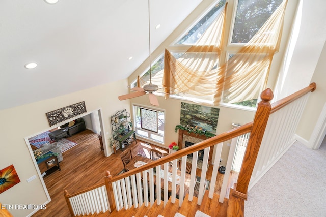 staircase featuring a ceiling fan, baseboards, high vaulted ceiling, recessed lighting, and a fireplace