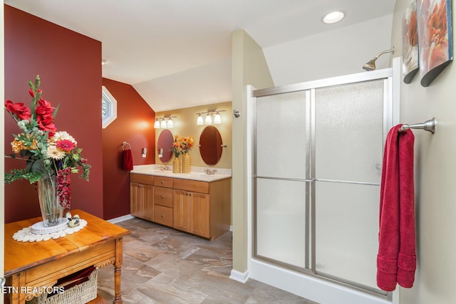 bathroom with baseboards, double vanity, a stall shower, a sink, and vaulted ceiling