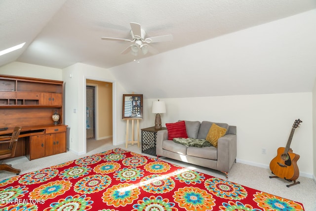 carpeted living area featuring ceiling fan, lofted ceiling with skylight, baseboards, and a textured ceiling