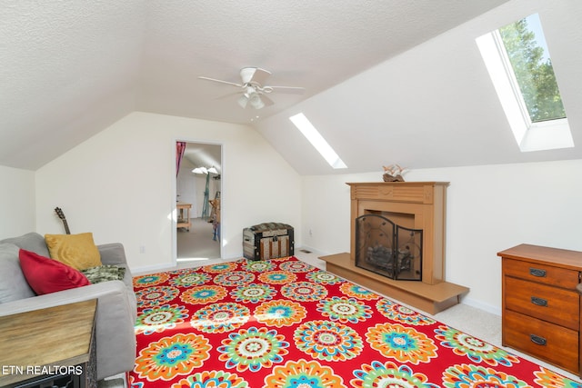 interior space with lofted ceiling with skylight, a ceiling fan, carpet floors, and a textured ceiling