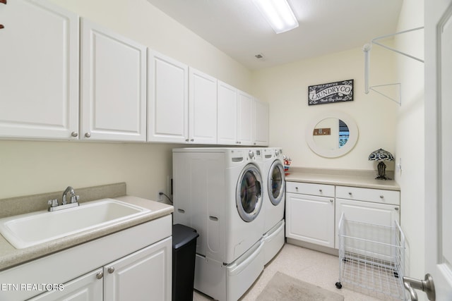 washroom with a sink, visible vents, cabinet space, and washing machine and clothes dryer