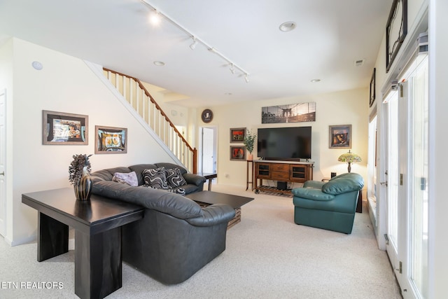 carpeted living room with rail lighting and stairs