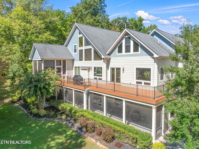 back of property featuring a yard, roof with shingles, and a sunroom