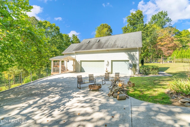 exterior space with an outbuilding, fence, an outdoor fire pit, concrete driveway, and a garage