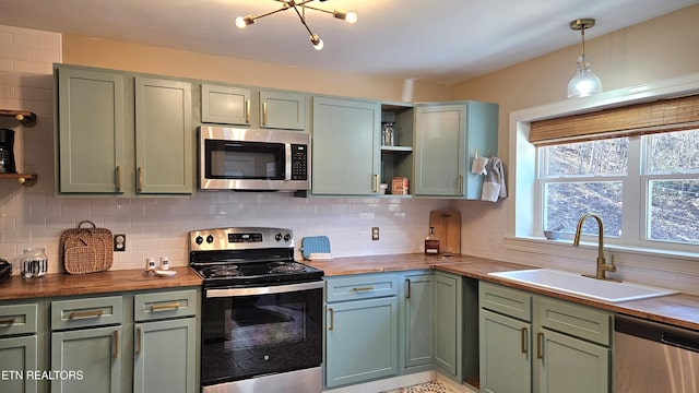 kitchen featuring butcher block countertops, stainless steel appliances, green cabinets, and a sink