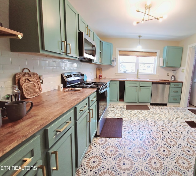 kitchen featuring green cabinetry, a sink, butcher block countertops, stainless steel appliances, and tasteful backsplash