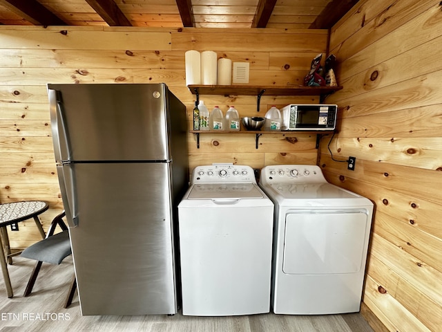 clothes washing area with wooden walls, wood finished floors, laundry area, separate washer and dryer, and wooden ceiling