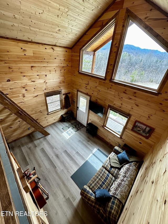 unfurnished living room featuring wood walls, wood ceiling, wood finished floors, a mountain view, and high vaulted ceiling