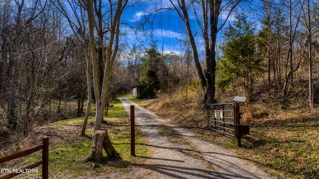 view of street featuring a wooded view and a gate