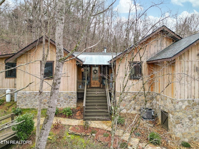 rustic home featuring stone siding and stairs