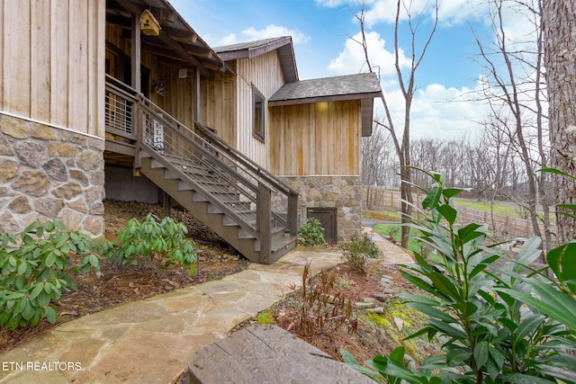 view of property exterior with stone siding and stairway