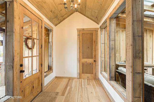 interior space featuring light wood-type flooring, lofted ceiling, an inviting chandelier, baseboards, and wood ceiling