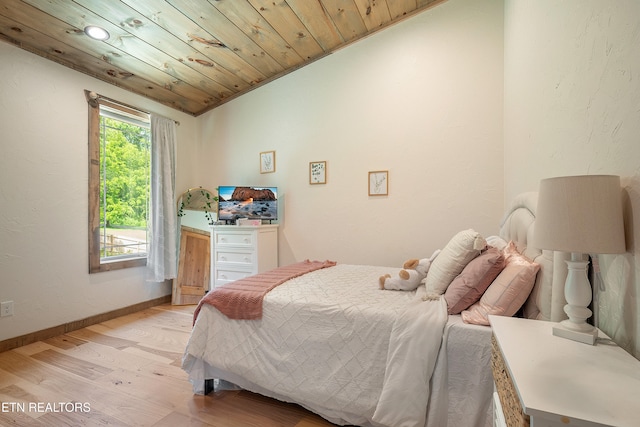 bedroom with baseboards, wood ceiling, lofted ceiling, light wood-style flooring, and a textured wall