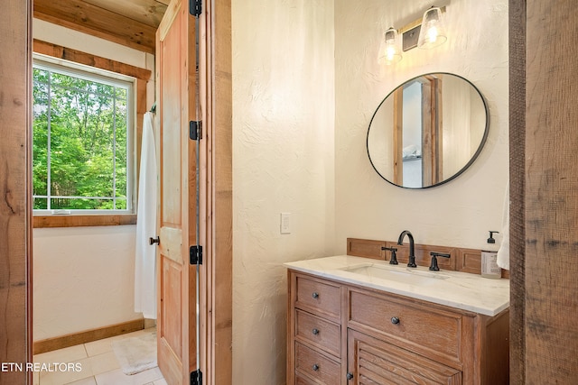 bathroom with tile patterned floors, vanity, baseboards, and a textured wall