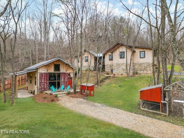 view of front facade featuring a front yard, an outdoor structure, crawl space, stone siding, and driveway