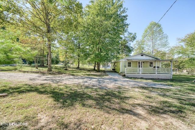 view of yard featuring covered porch and dirt driveway