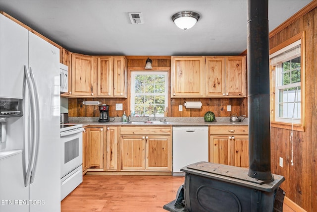 kitchen featuring a sink, visible vents, white appliances, and wood walls