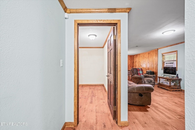 hallway with light wood finished floors, crown molding, and baseboards