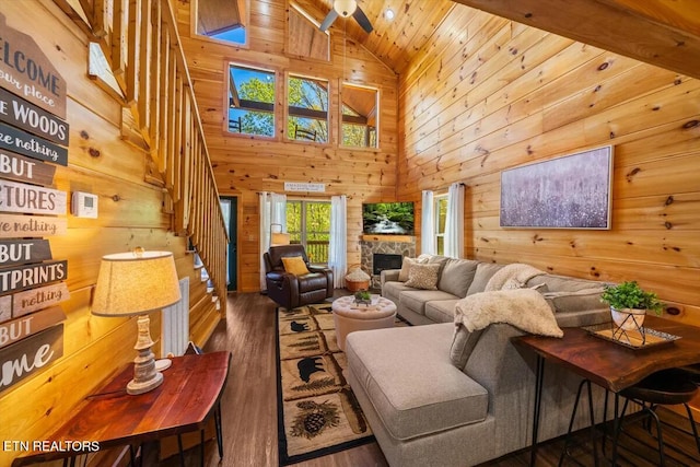 living area featuring wooden walls, wood ceiling, a fireplace, wood finished floors, and high vaulted ceiling