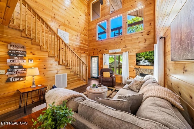 living room with wooden walls, visible vents, stairs, a fireplace, and wood finished floors