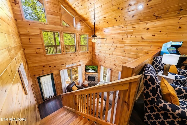 stairs featuring wood walls, a fireplace, wooden ceiling, and wood finished floors