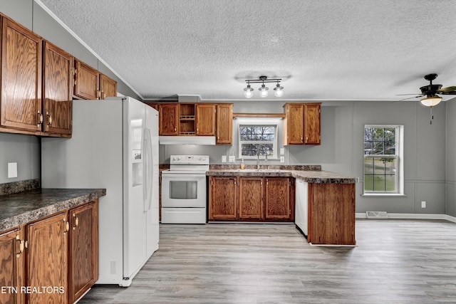 kitchen featuring white appliances, dark countertops, brown cabinets, and light wood finished floors