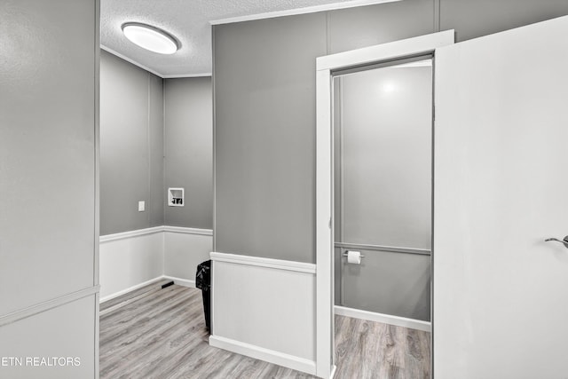 laundry area featuring hookup for a washing machine, a textured ceiling, and wood finished floors