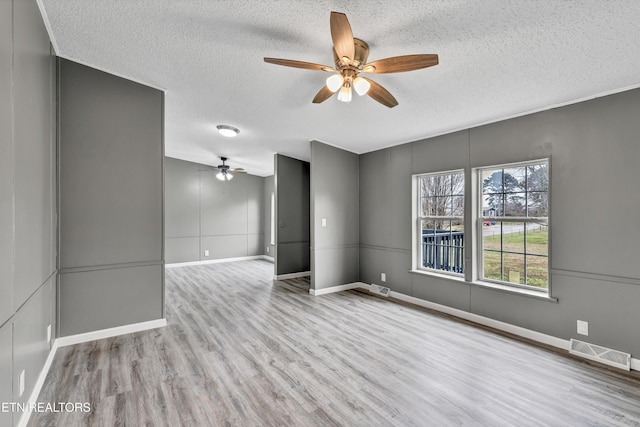 empty room featuring visible vents, a textured ceiling, baseboards, and wood finished floors