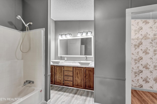 bathroom with wood finished floors, a textured ceiling,  shower combination, and a sink