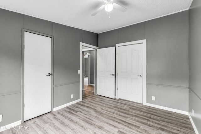 unfurnished bedroom featuring crown molding, baseboards, ceiling fan, wood finished floors, and a textured ceiling