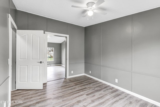 empty room featuring a decorative wall, a textured ceiling, a ceiling fan, and wood finished floors