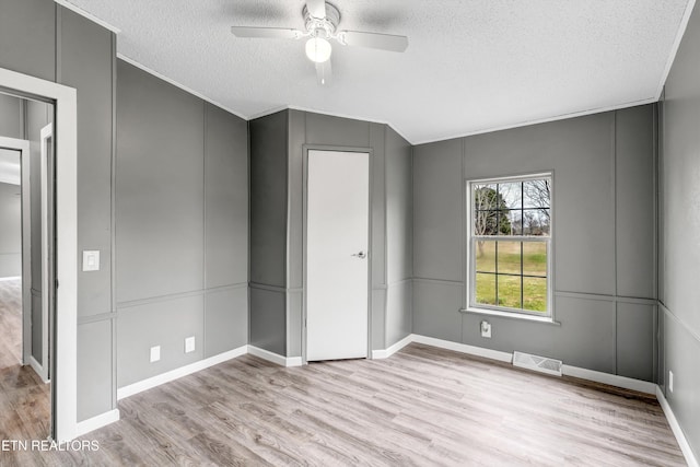 unfurnished bedroom with visible vents, wood finished floors, and a decorative wall