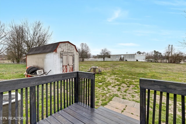 wooden terrace featuring a storage shed, a yard, and an outbuilding