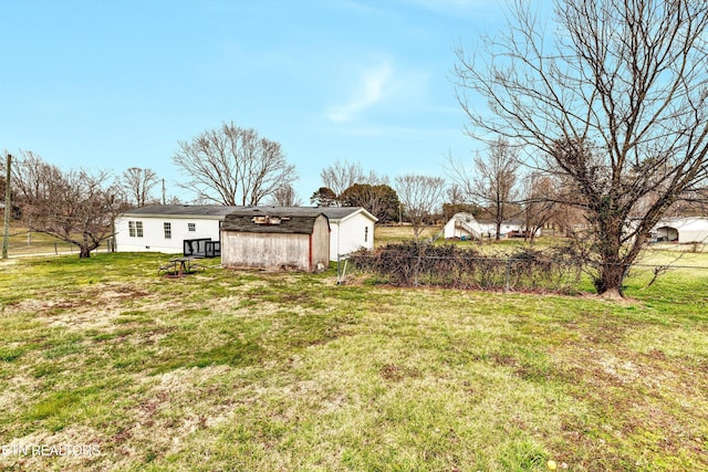 view of yard featuring a storage shed, an outdoor structure, and fence