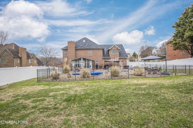 back of property with a patio area, a yard, a fenced backyard, and brick siding