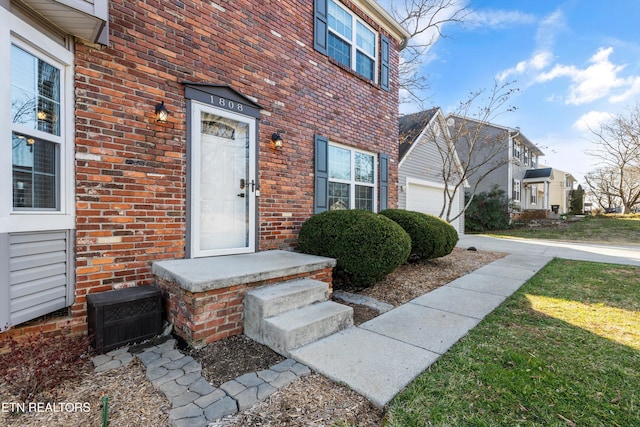 view of exterior entry featuring brick siding and a garage