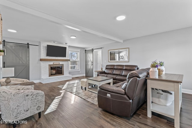 living room featuring a barn door, baseboards, beamed ceiling, and wood finished floors