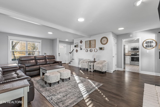 living room featuring stairway, wood finished floors, beamed ceiling, and baseboards