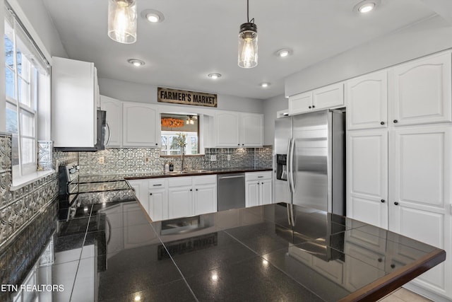 kitchen featuring dark countertops, decorative backsplash, a peninsula, and stainless steel appliances