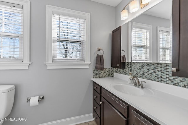 bathroom featuring a wealth of natural light, baseboards, backsplash, and vanity