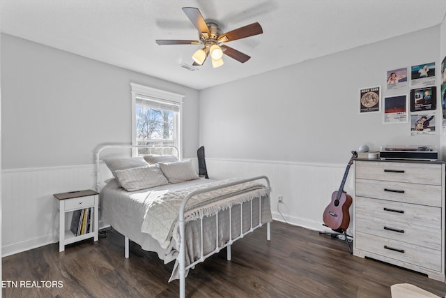 bedroom featuring a wainscoted wall, visible vents, a ceiling fan, and wood finished floors