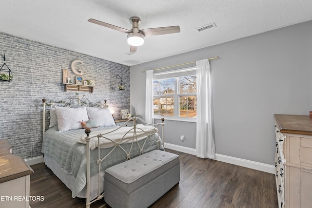 bedroom with wood finished floors, baseboards, brick wall, and a textured ceiling