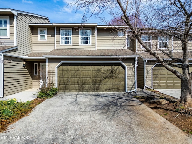 townhome / multi-family property with aphalt driveway, an attached garage, and roof with shingles