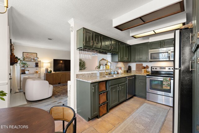 kitchen with green cabinetry, a sink, appliances with stainless steel finishes, a textured ceiling, and crown molding