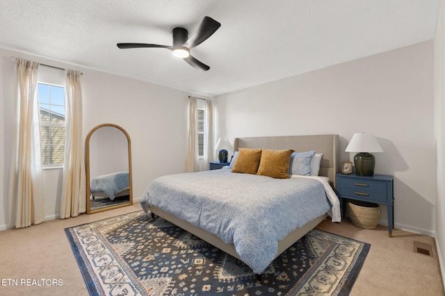 carpeted bedroom with visible vents, baseboards, a textured ceiling, and ceiling fan