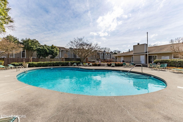 community pool featuring a residential view, a patio, and fence